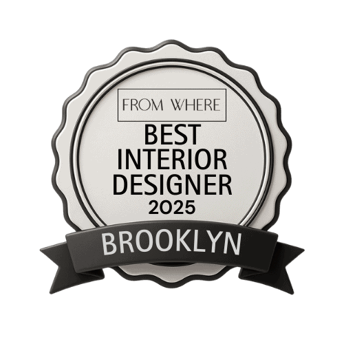 Best Interior Designer Brooklyn 2025 A large mirror hangs over the custom marble-clad fireplace with roots in early modern architecture, a large coffee table, and a pair of French Art Deco armchairs with sinuous wood arms and a ‘Hocker Stool’ designed by Herzog and de Meuron sit on a striped flat weave rug.